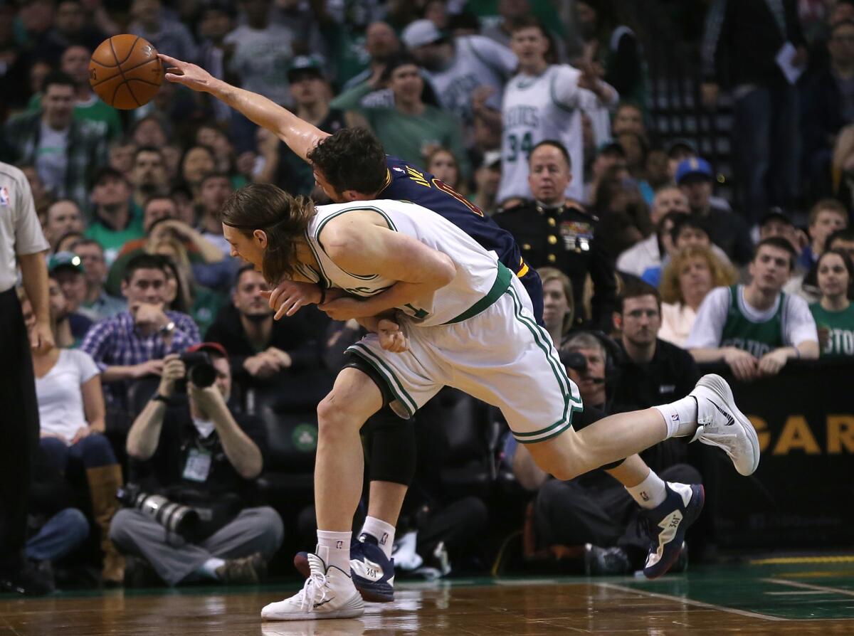 Celtics forward Kelly Olynyk pulls on Cavaliers power forward Kevin Love's arm to keep him away from a loose ball.