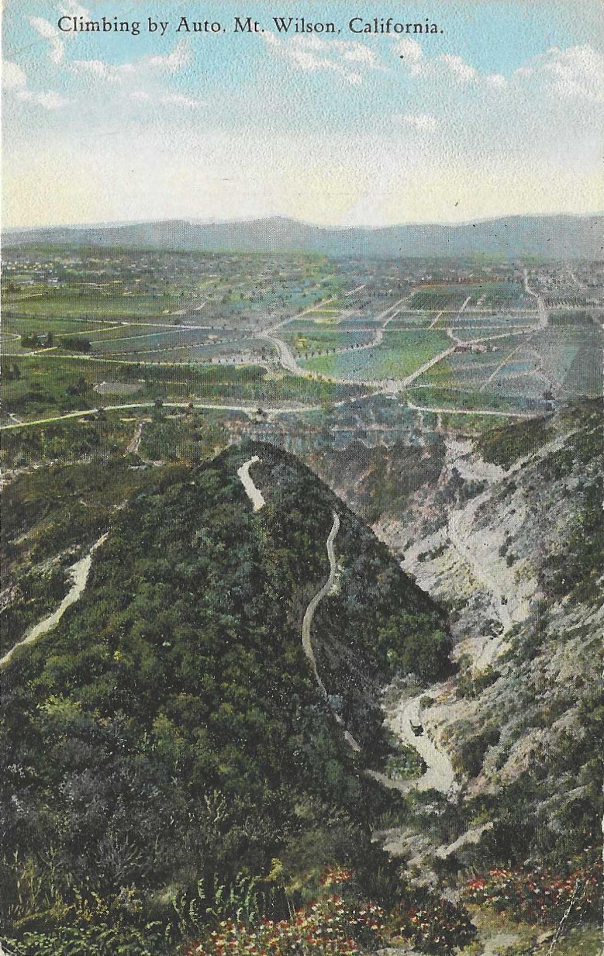 A vintage postcard looks at Los Angeles from the San Gabriel Mountains and reads "Climbing by Auto, Mt. Wilson, California"