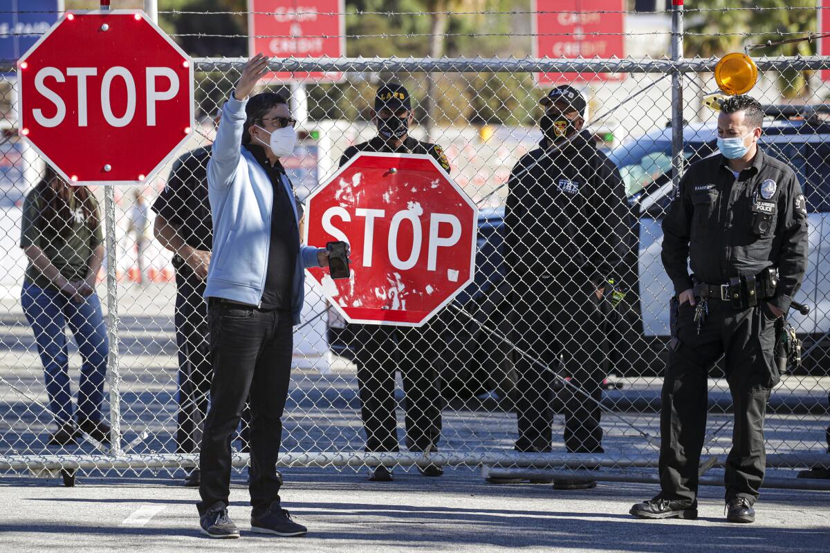 A man stands outside a gate with law officers nearby.