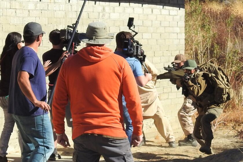 Actors with guns, Ryan Stuart, l, and Julia Ling, r, shown in behind-the-scenes filming of 2019 film "Tango Down."