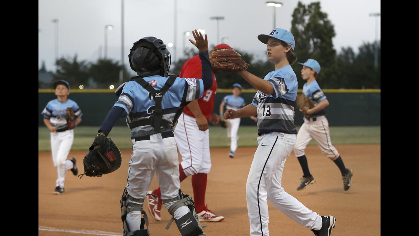 Newport Beach Baseball Assn. starting pitcher Jamey Ott (13) and catcher Garrett Ip high five after closing out the top of the second inning against Tustin in the PONY Bronco 11-and-under section tournament at Fountain Valley Sports Park on Thursday, June 28.
