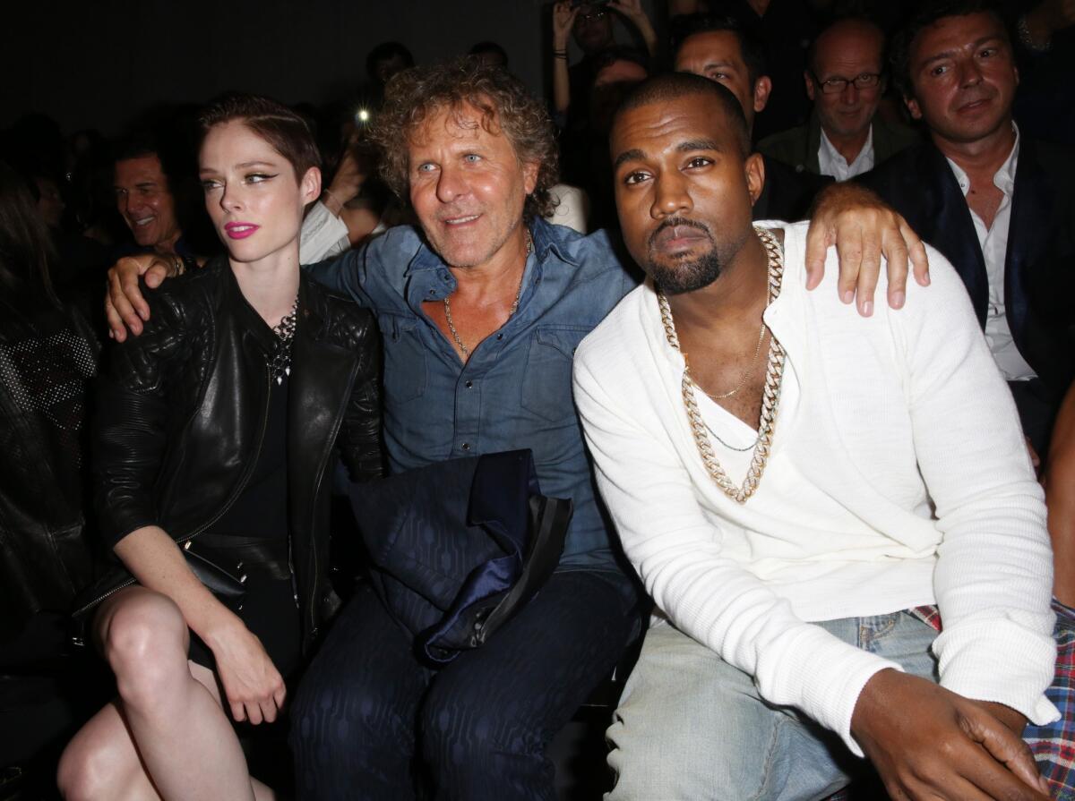 Kanye West, right, watches the Diesel Black Gold fashion show with model Coco Rocha, left and designer Renzo Russo during New York Fashion Week in early September.