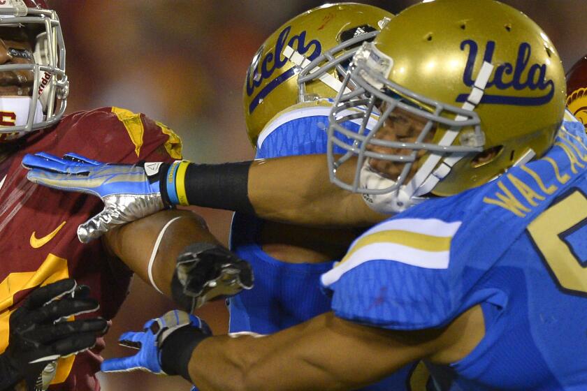 UCLA linebacker Aaron Wallace, right, battles USC tight end Xavier Grimble during the Bruins' win in November.