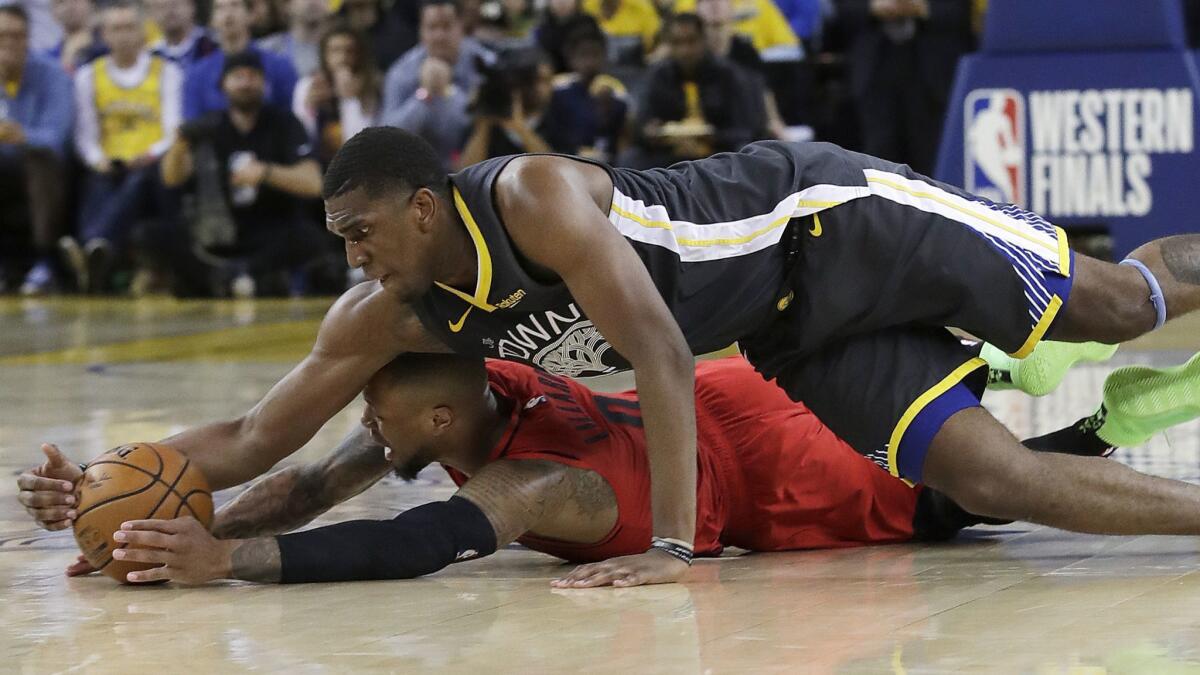 Golden State Warriors center Kevon Looney, top, reaches for the ball over Portland Trail Blazers guard Damian Lillard during the second half of Game 2 of the NBA Western Conference finals on May 16. Lillard suffered separated ribs on the play.