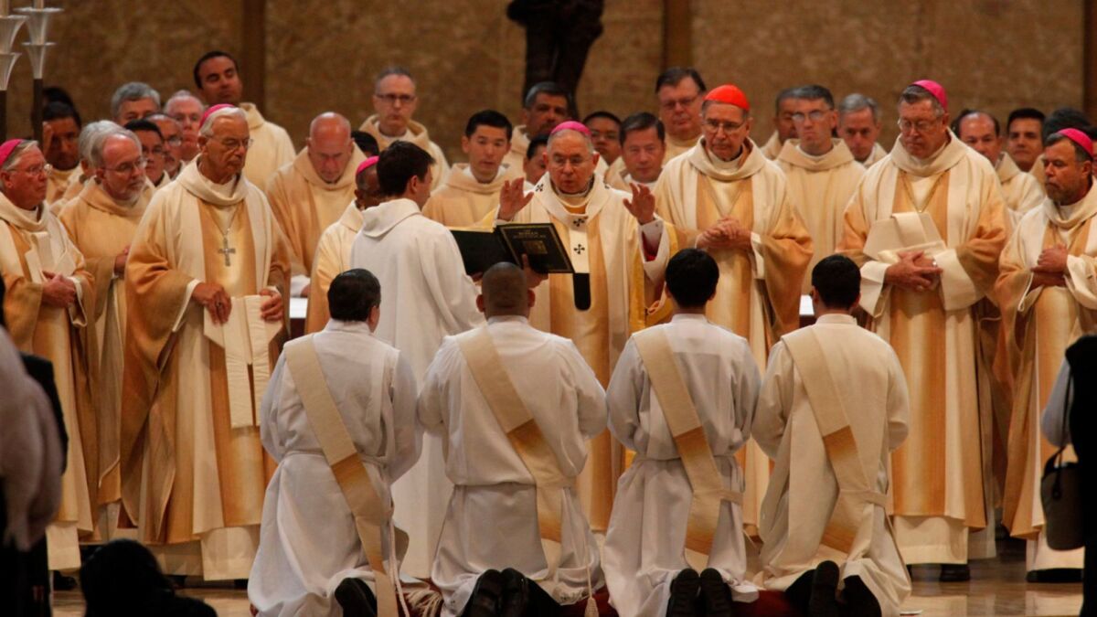 Los Angeles Archbishop Jose H. Gomez says a prayer over new Catholic priests during their ordination in 2014. The number of priests has dropped by more than 30% in the U.S. since 1965..