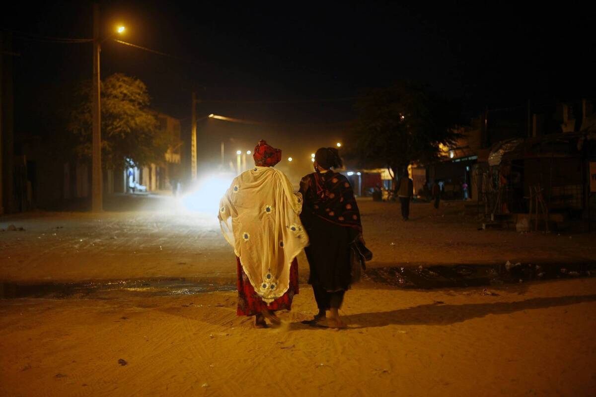 Women walk through Timbuktu, Mali, on Feb. 2, moments after the street lights came back on for the first time in months. The town's occupation by Islamic extremists made life difficult for residents until French and Malian forces drove the militants out.