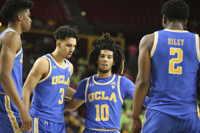 With his team down by double digits to Arizona State, UCLA's Tyger Campbell (10) gathers his teammates Chris Smith, left, Jules Bernard (3) and Cody Riley (2) during the second half of an NCAA college basketball game, Thursday, Feb. 6, 2020, in Tempe, Ariz. (AP Photo/Darryl Webb)