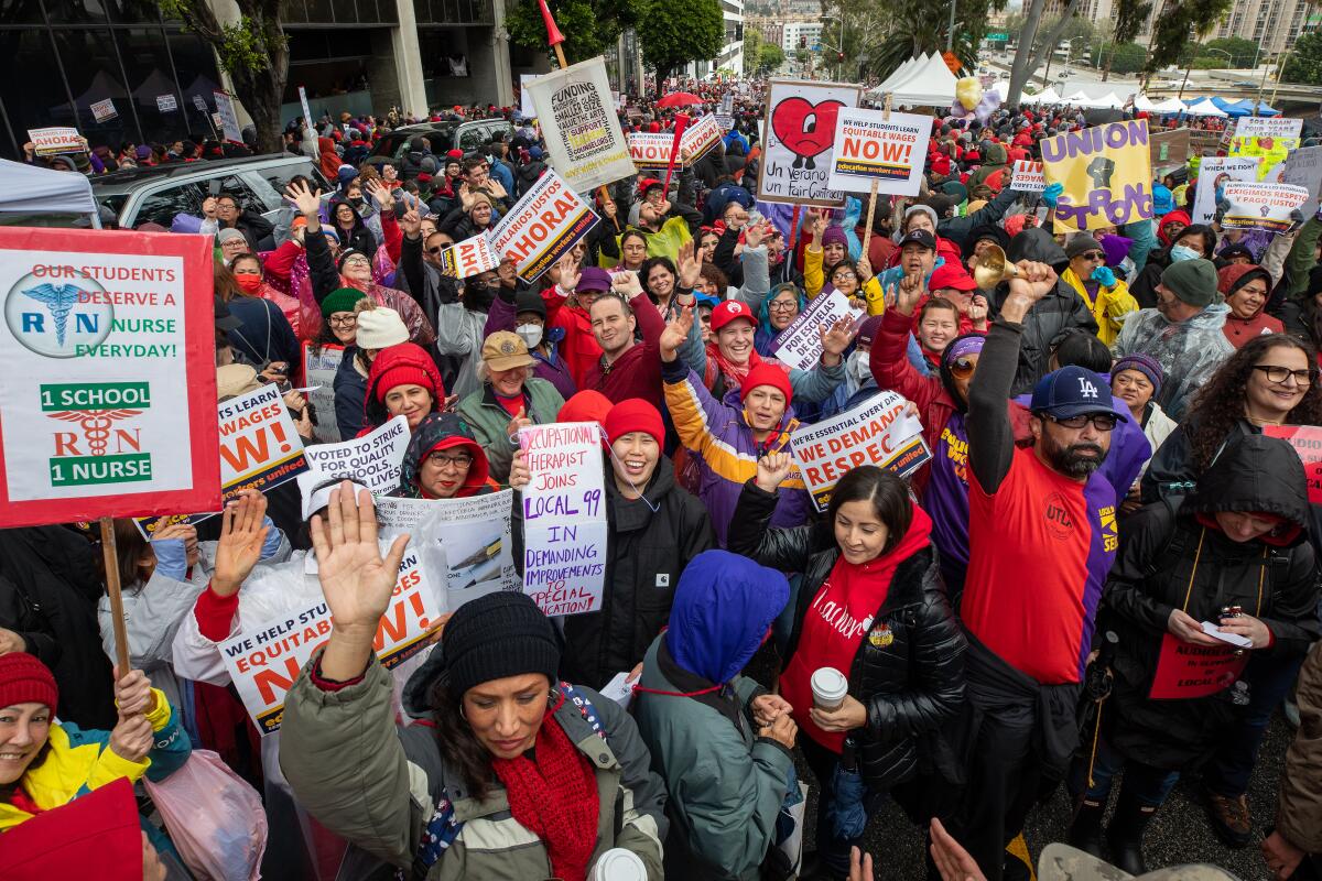 A large group of people stand together holding signs  