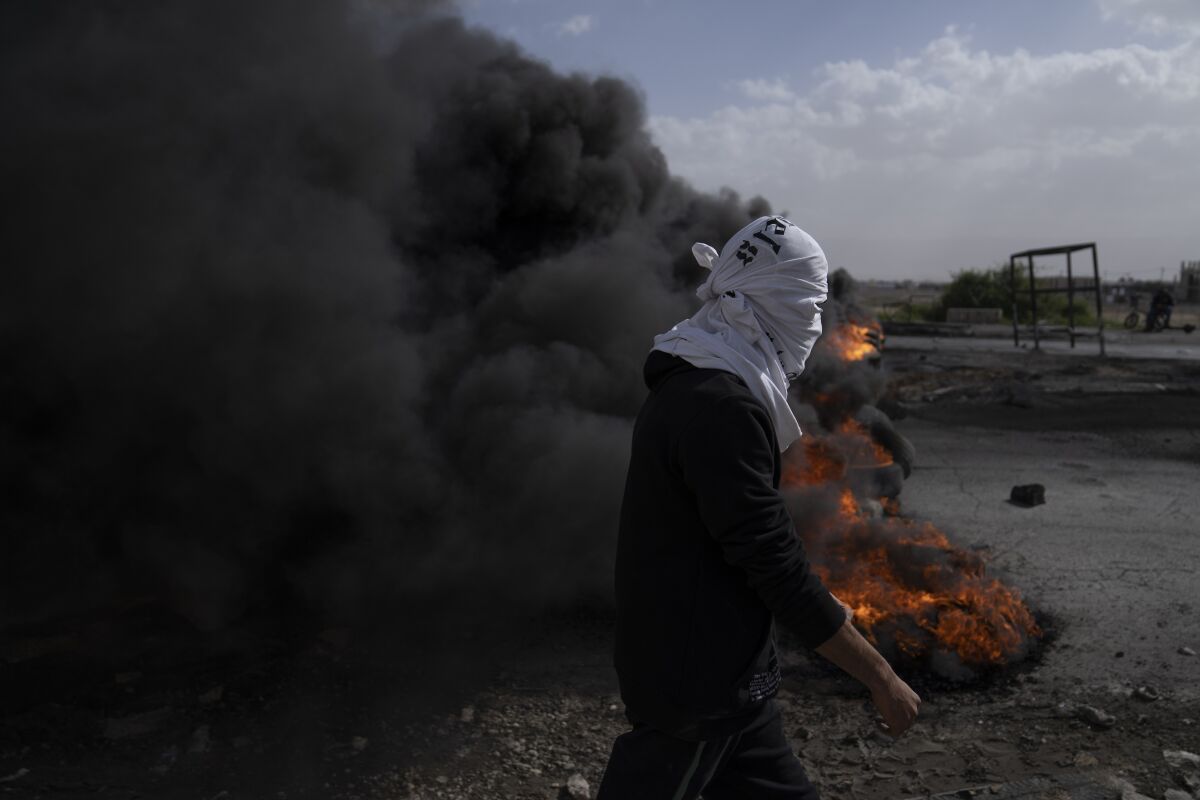 Palestinian protesters blocking road with burning tires