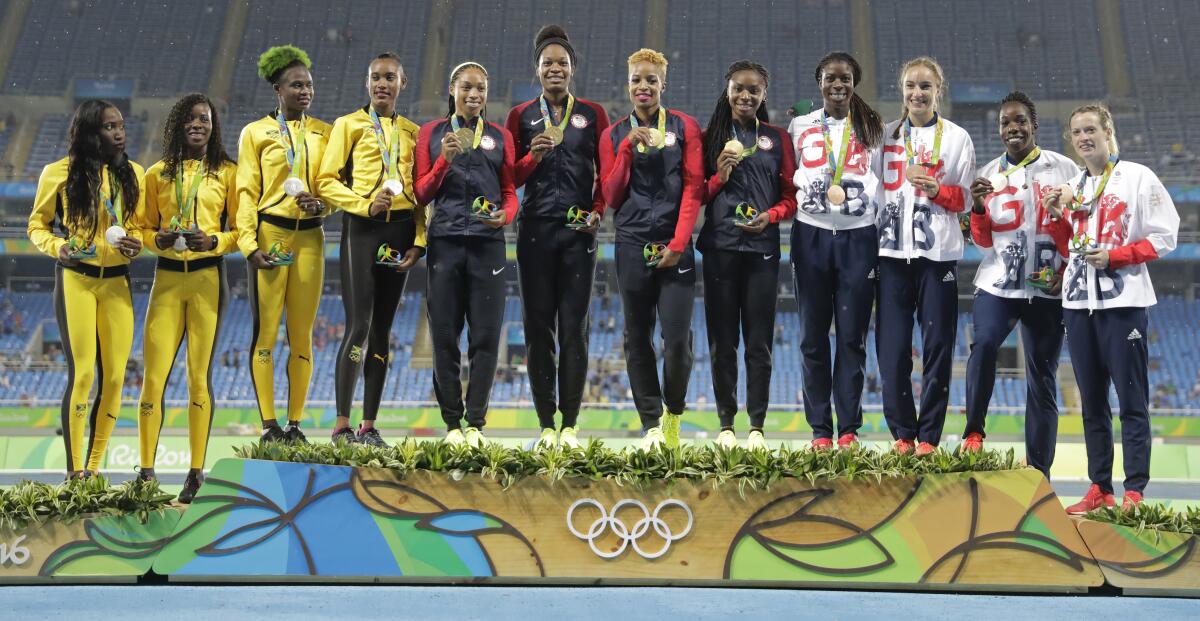 Olympic athletes stand in a line on the medals podium.