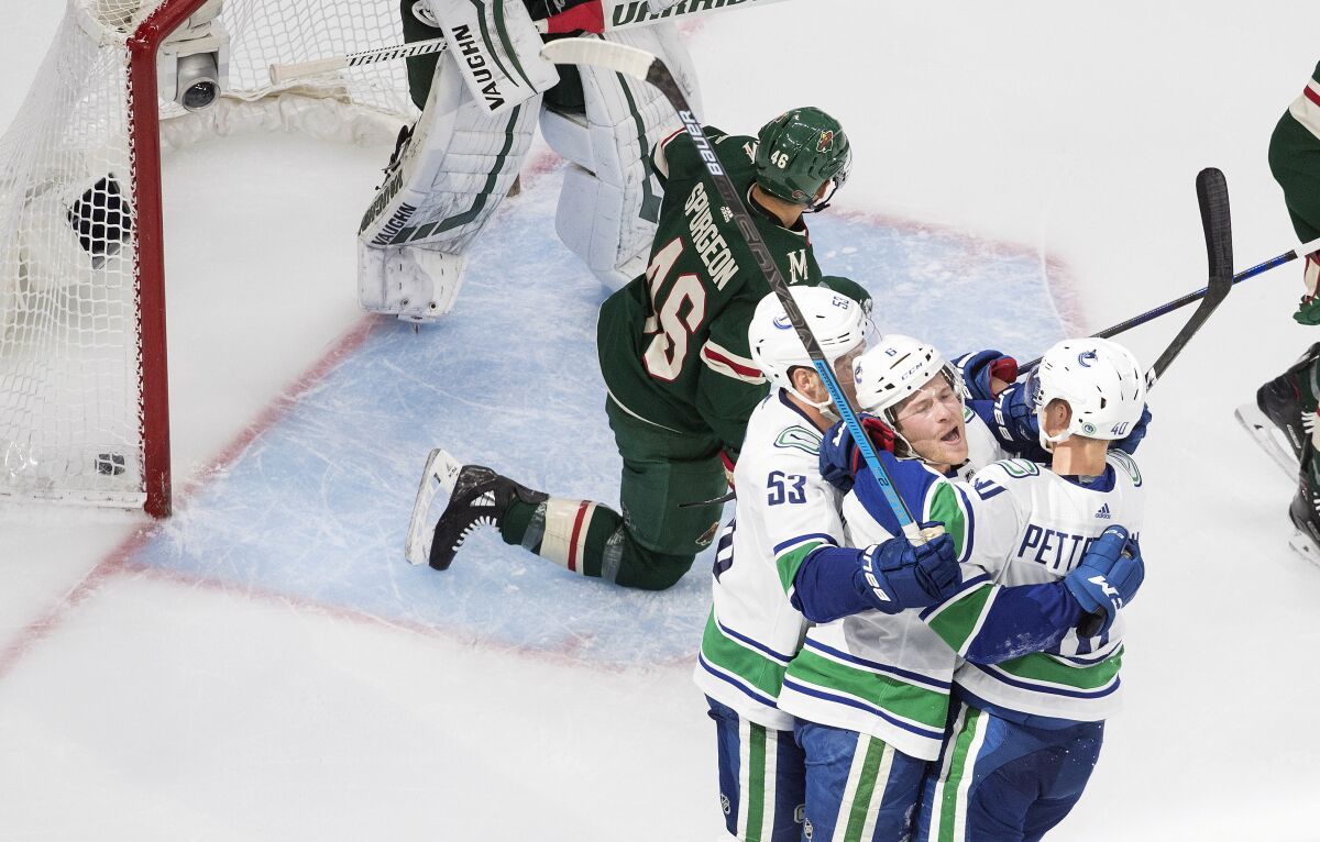 Minnesota Wild's Jared Spurgeon (46) kneels as Vancouver Canucks' Bo Horvat (53), Brock Boeser (6) and Elias Pettersson (40) celebrate a goal during second-period NHL hockey game action in Edmonton, Alberta, Thursday, Aug. 6, 2020. (Jason Franson/The Canadian Press via AP)