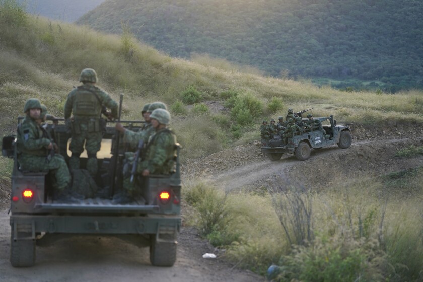 FILE - Soldiers patrol near the hamlet Plaza Vieja in the Michoacan state of Mexico, Oct. 28, 2021. The self-defense movement in the nearby town of Tepalcatepec, said improvised land mines severely damaged an army armored car on Saturday, Jan. 29, 2022. In the war raging between drug cartels in western Mexico, gangs have begun using improvised explosive devices (IEDs) on roads to disable army vehicles. (AP Photo/Eduardo Verdugo, File)