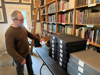 A man stands in an office lined with tall bookshelves.