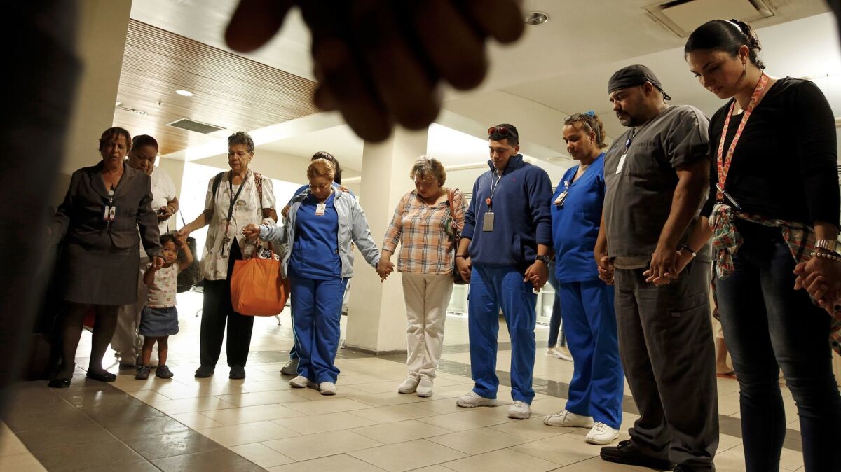 Hospital workers in San Juan pray for a colleague badly hurt in a carjacking en route to work in the post-hurricane chaos. Some doctors cannot even get to the hospital because the roads are not cleared yet, said Puerto Rico Medical Center s Dr. Charlie Gomez.