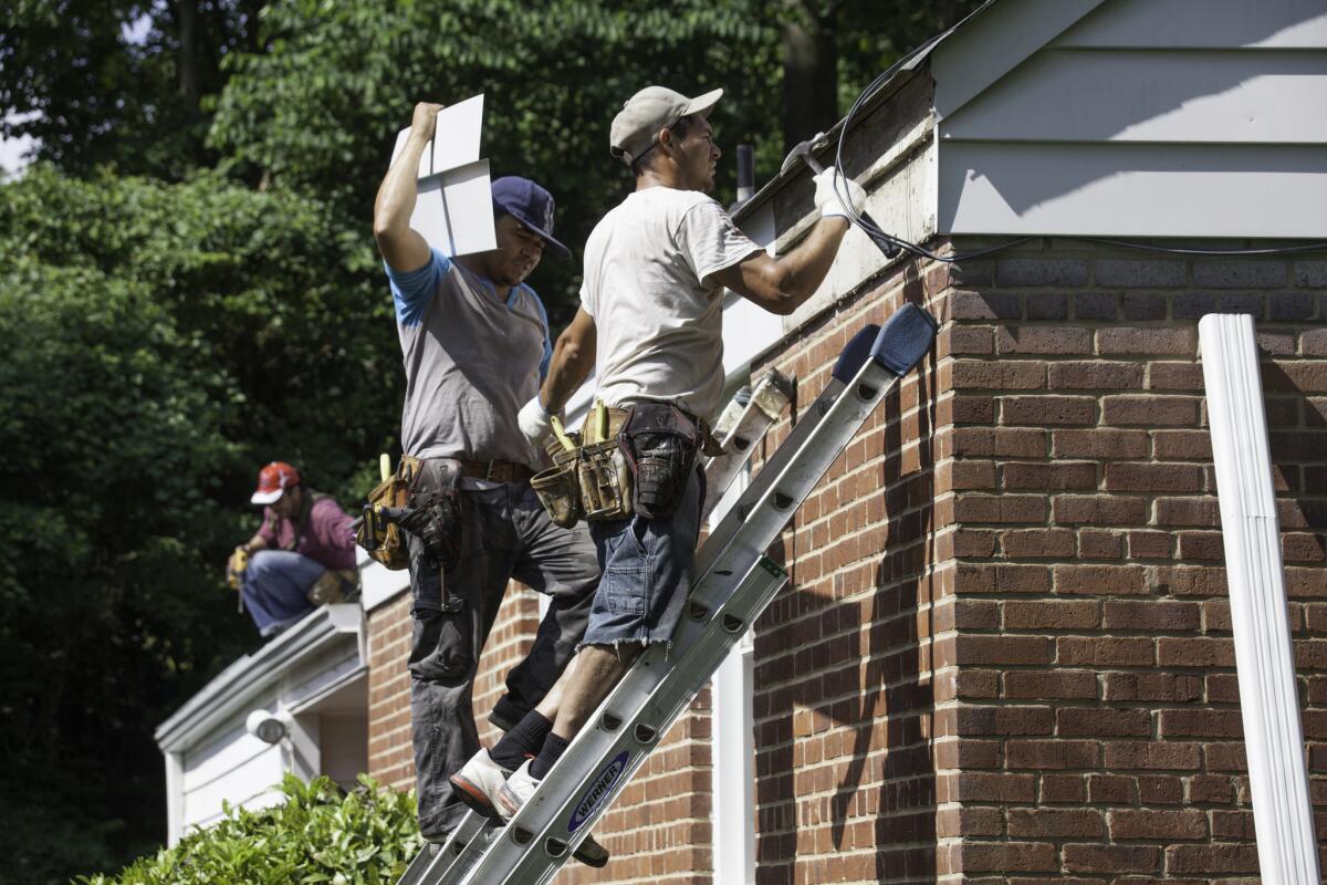 Workers from El Salvador and Honduras replace a home's roof and gutters in Fairfax County, Va., last week. Census Bureau figures show that Latino immigrant population growth in the U.S. has been overtaken by Asians in the last two years.