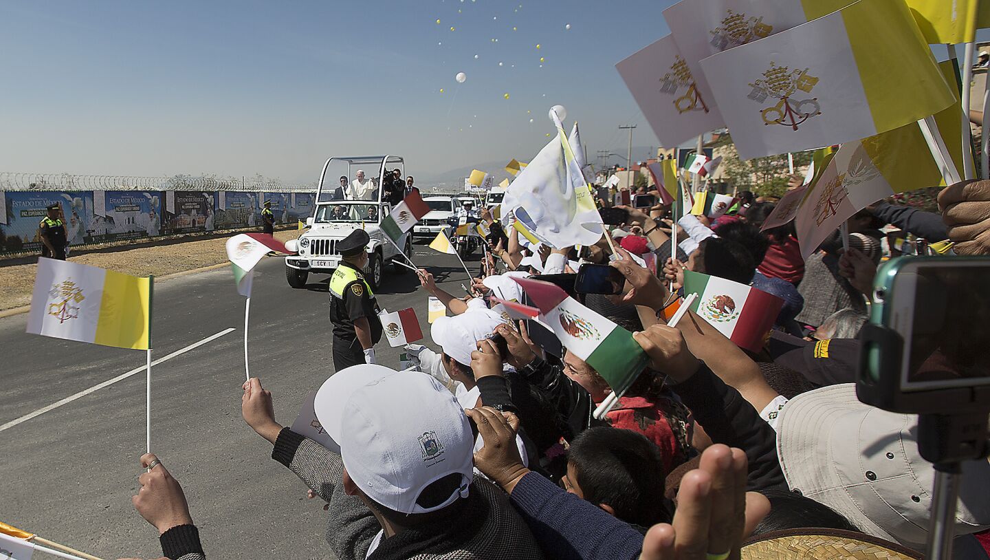 People lining Pope Francis' route wave as he and his motorcade arrive in Ecatepec, a suburb northeast of Mexico City.