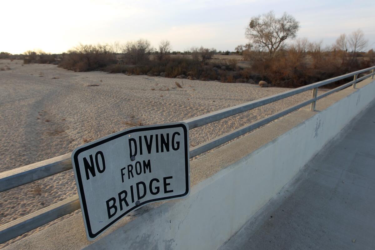 A sign from wetter times warns people not to dive from a bridge over the Kern River, which has been dried up by water diversion projects and a shortage of rain, in Bakersfield.