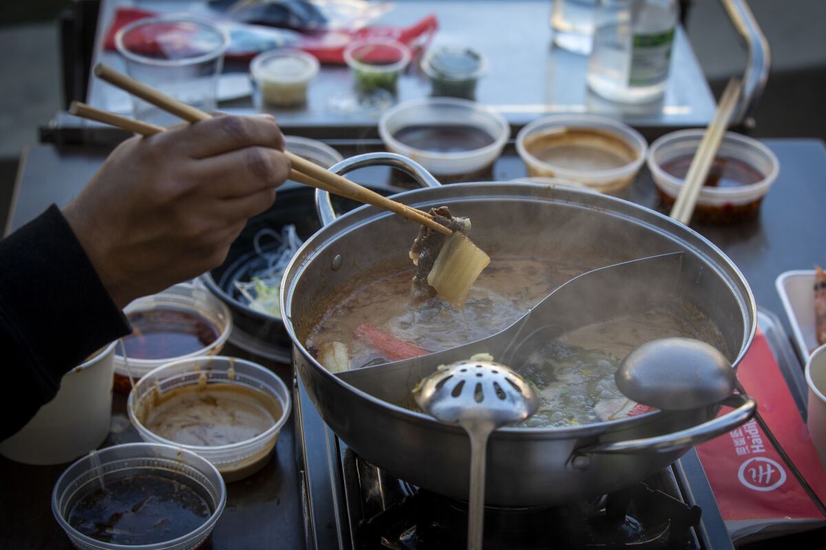 People dip chopsticks into Hot Pot