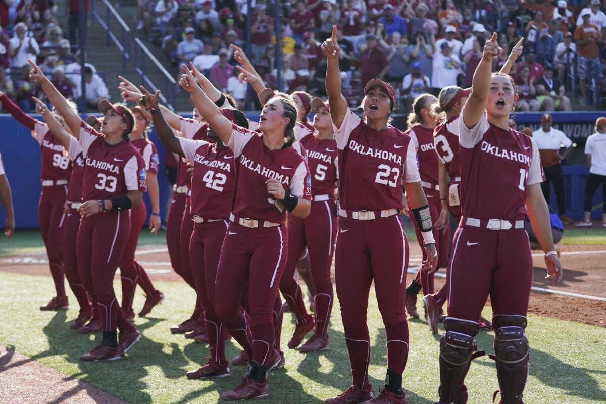 Oklahoma players gesture to fans before the Women's College World Series championship series against Texas.