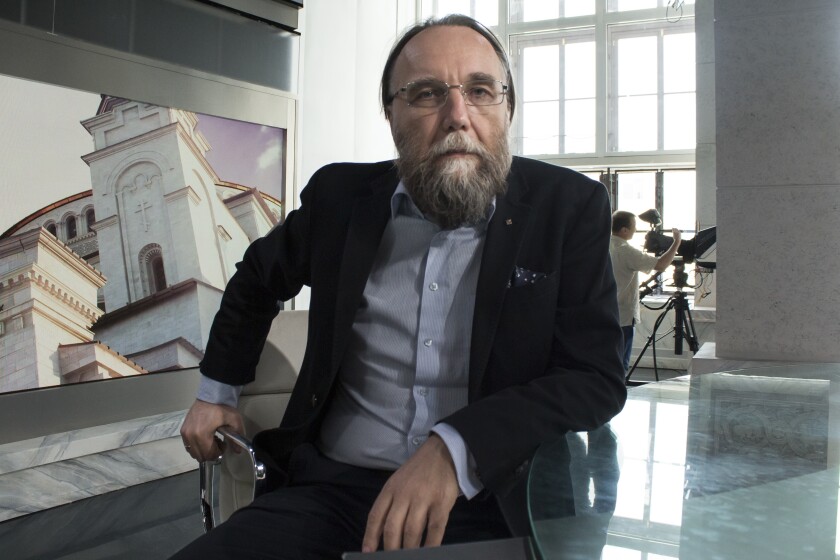 Alexander Dugin sits in a chair in a room.
