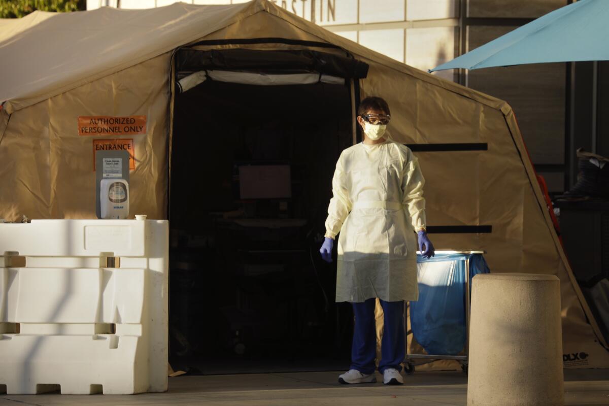 A hospital worker waits for patients at a screening tent outside Ronald Reagan UCLA Medical Center.