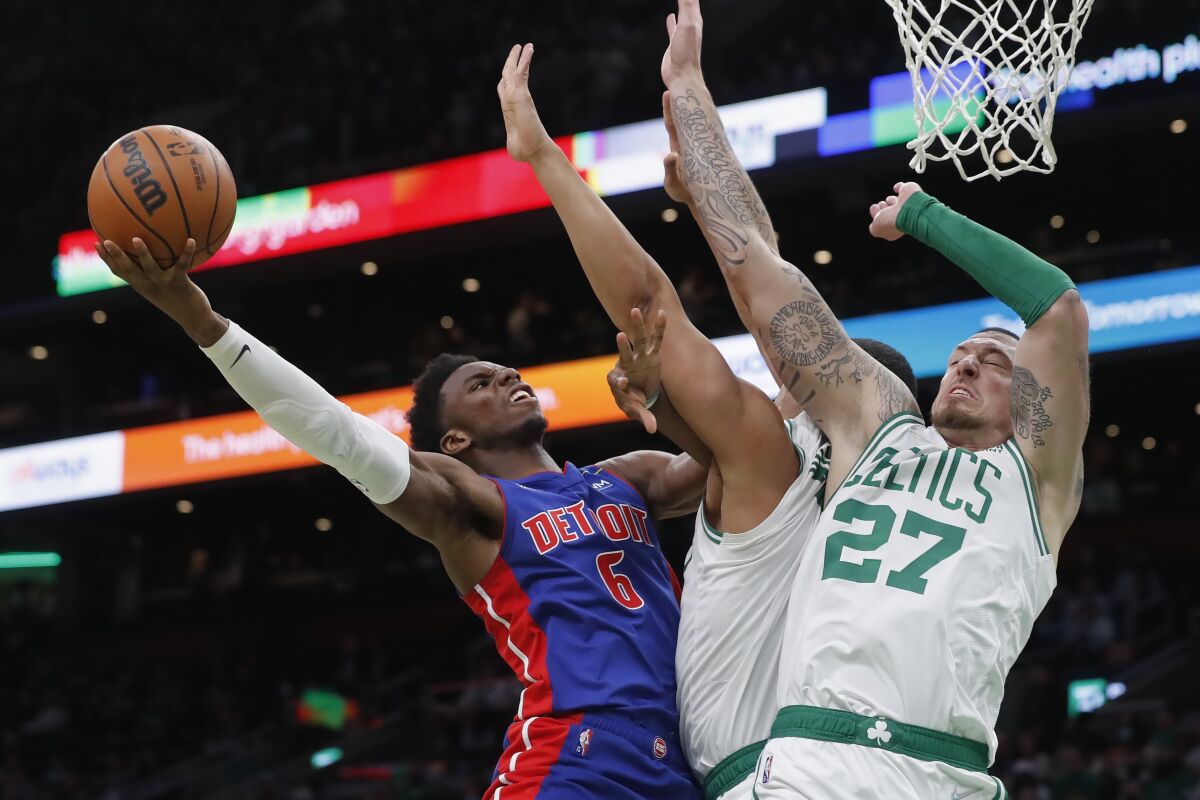 Detroit Pistons' Hamidou Diallo (6) shoots against Boston Celtics' Daniel Theis (27) and Grant Williams, center, during the second half of an NBA basketball game, Wednesday, Feb. 16, 2022, in Boston. (AP Photo/Michael Dwyer)