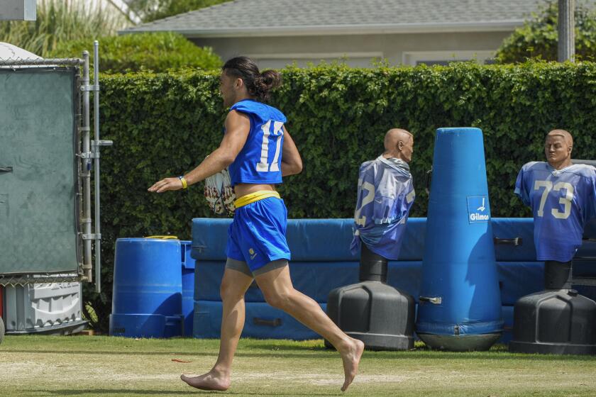 Rams wide receiver Puka Nacua (17) walks on the practice field sideline in bare feet.