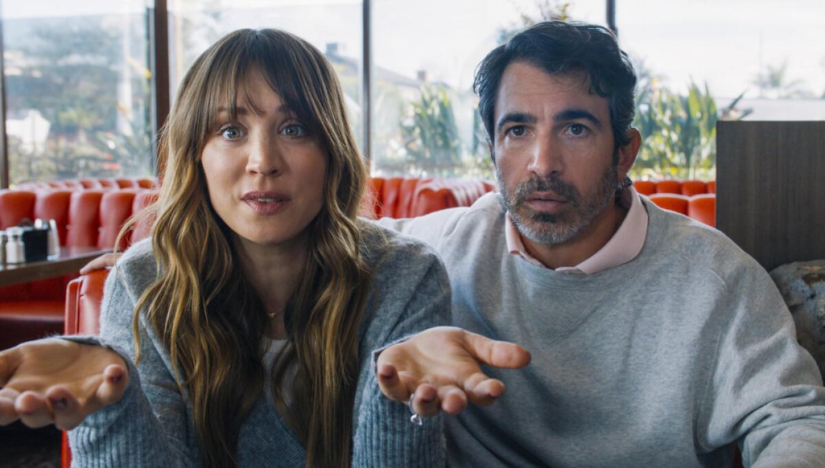 A woman with long brown hair sits next to a man in a restaurant booth.