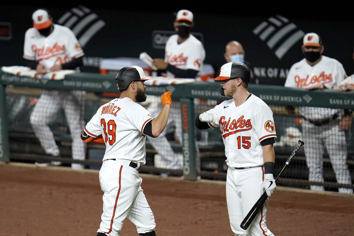 Baltimore Orioles' Renato Nunez, left, is greeted near the dugout by Chance Sisco after hitting a three-run home run off New York Mets starting pitcher Ariel Jurado during the first inning of a baseball game, Tuesday, Sept. 1, 2020, in Baltimore. Orioles' Cedric Mullins and Jose Iglesias scored on the home run. (AP Photo/Julio Cortez)