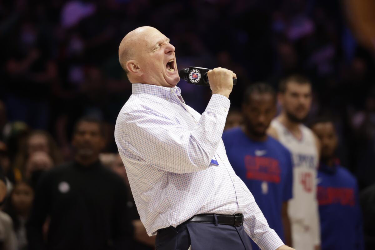 Clippers owner Steve Ballmer speaks loudly into a microphone as players watch.