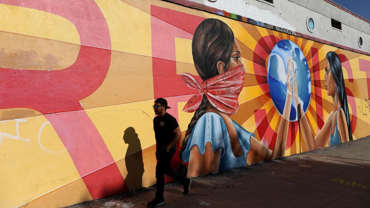 A man walks past a mural on Anderson Street in Boyle Heights that reads "RESIST."