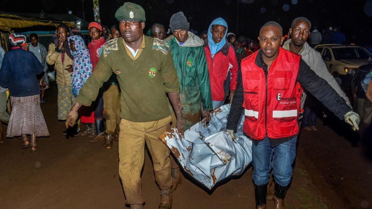 People carry a victim's body from a residential area after Patel dam burst its bank at Solai, Kenya, on May 10.