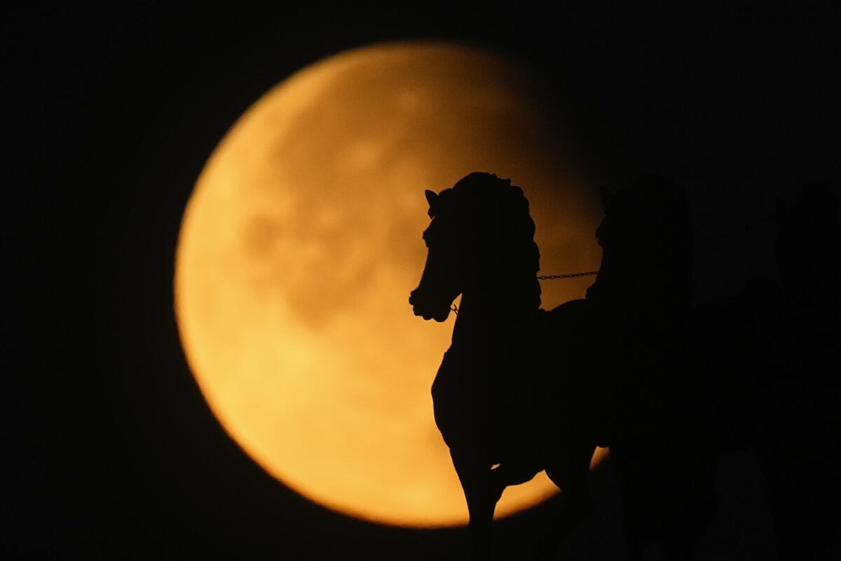 Supermoon rises behind a horse statue atop of Triumphal Arc during a partial lunar eclipse in Moscow, Russia, Sept. 18, 2024