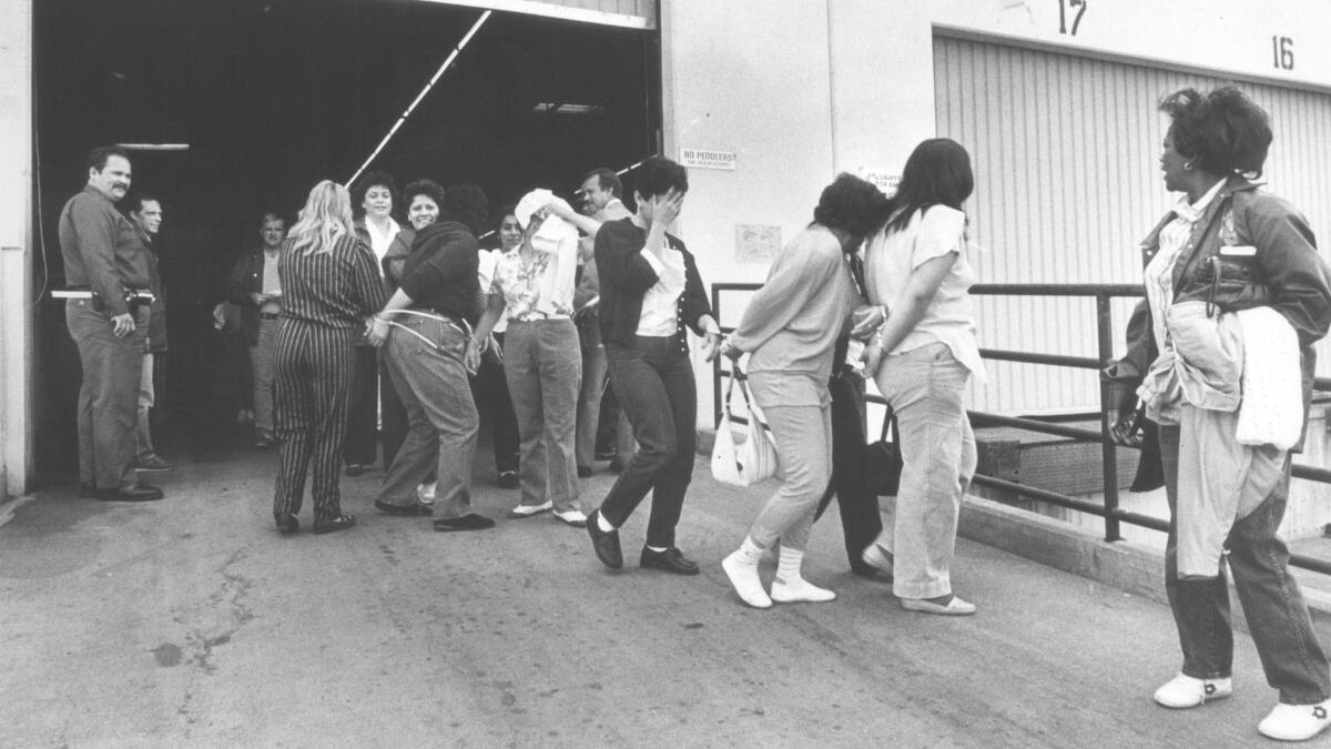 Immigration agents lead suspected illegal immigrants out of a workplace in the City of Industry in 1985.
