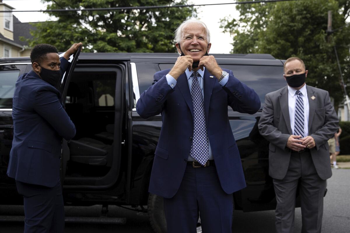 Joe Biden pulls down his mask as he makes an unannounced stop at his childhood home in Scranton, Pa.