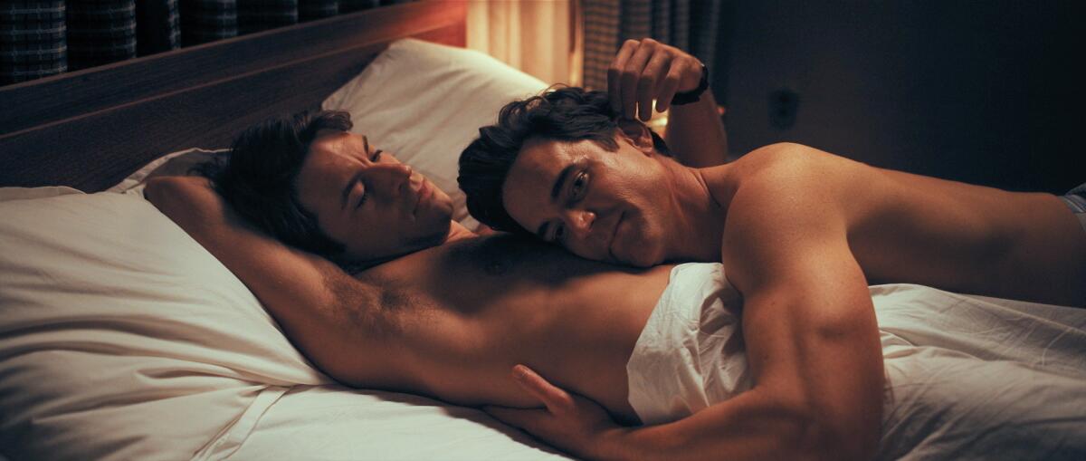 Two bare-chested men lie in bed caressing each other in "Fellow Travelers."