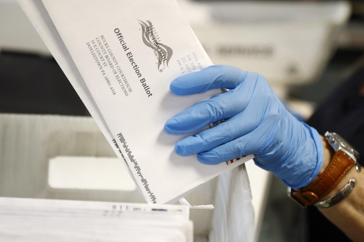A worker holds a mail-in ballot envelope at the Bucks County Board of Elections office in Doylestown, Pa., in May. 
