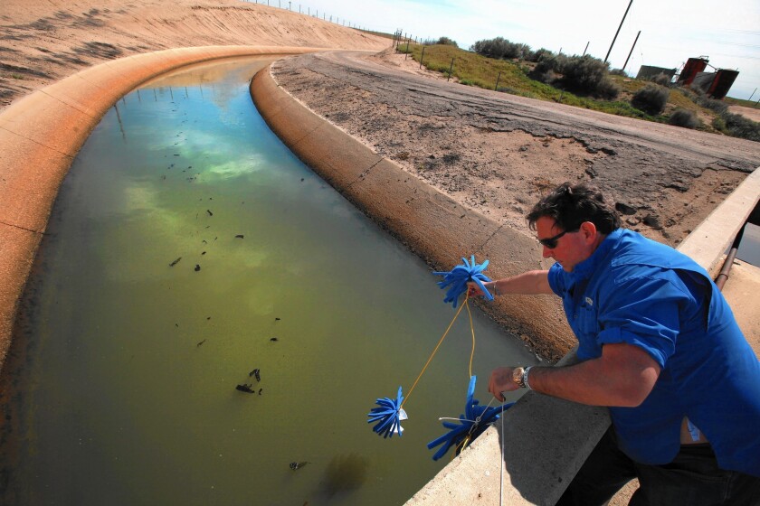 Scott Smith of advocacy group Water Defense collects samples in March from a canal operated by the Cawelo Water District, which buys treated oil field wastewater from Chevron.