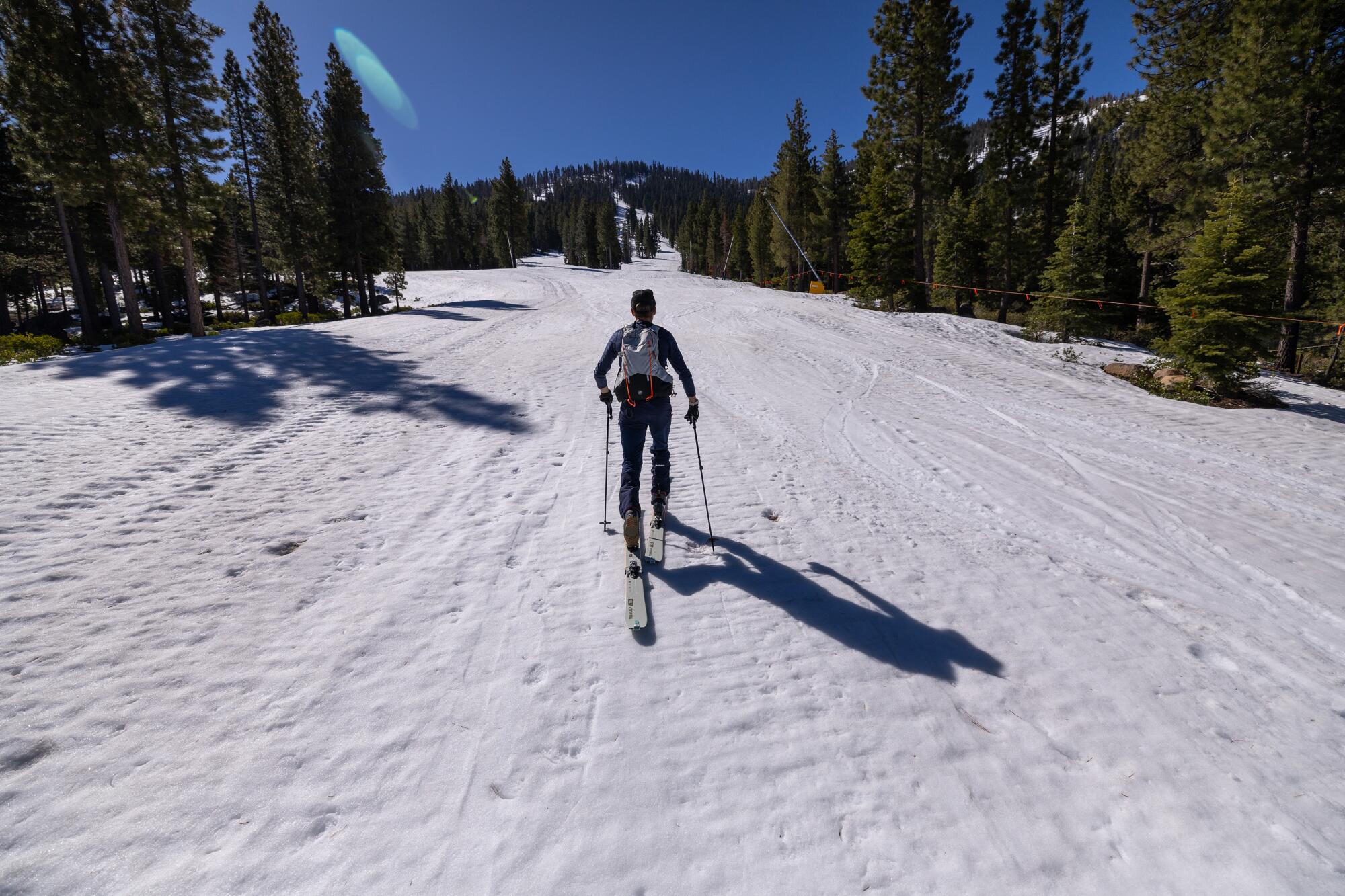 A man skis up a snowy slope.