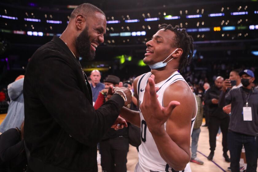 LOS ANGELES, CA - DECEMBER 04: Lebron James comes onto the court to congratulate his son Bronny James.