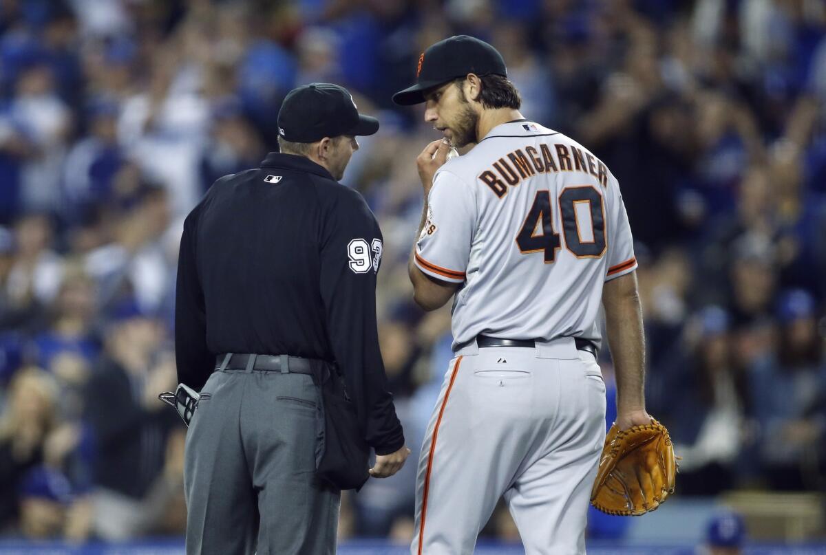San Francisco pitcher Madison Bumgarner, right, talks with home plate umpire Will Little, left, as Dodgers outfielder Yasiel Puig rounds the bases after hitting a solo home run.