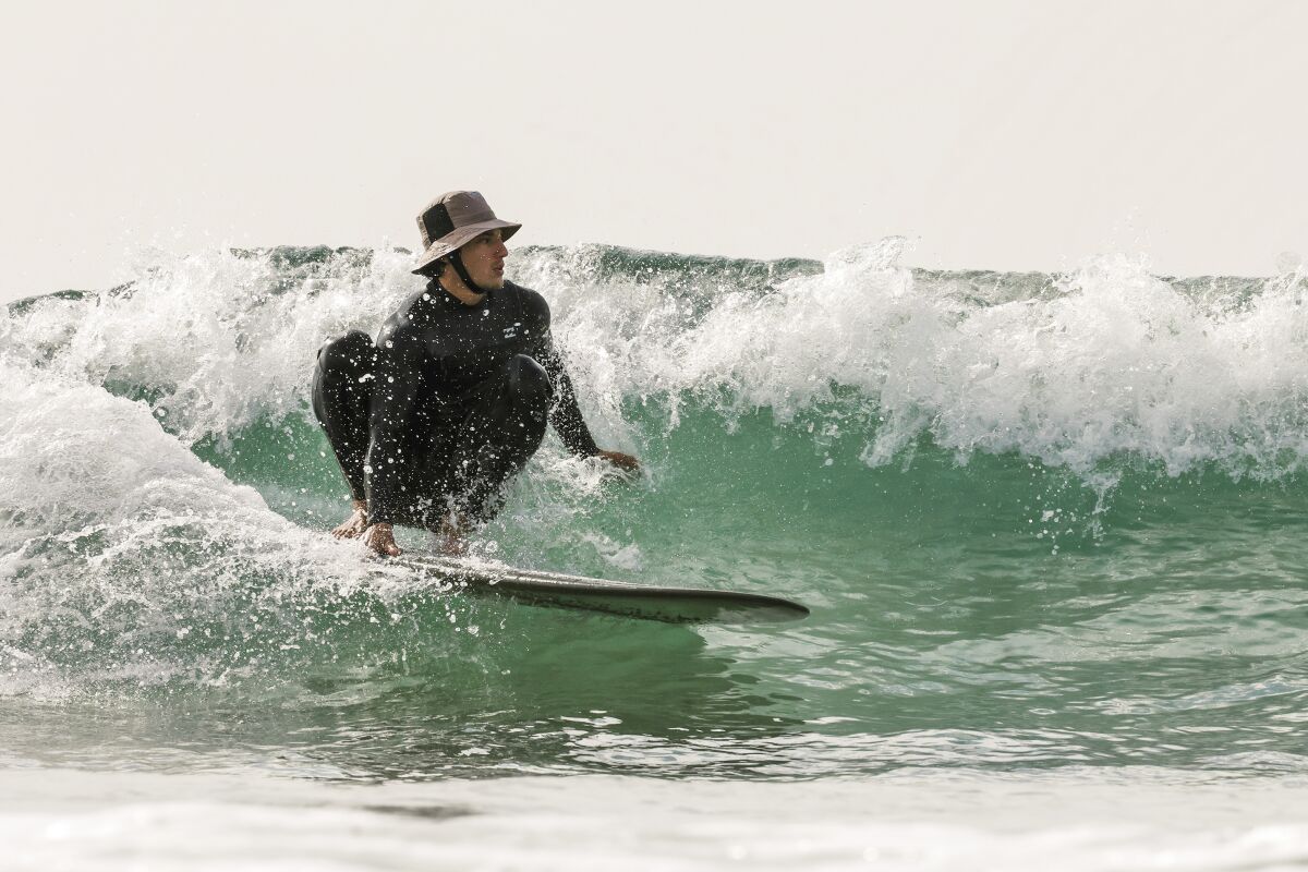 Gabe Verduzco crouches on his surfboard as he rides a wave. 