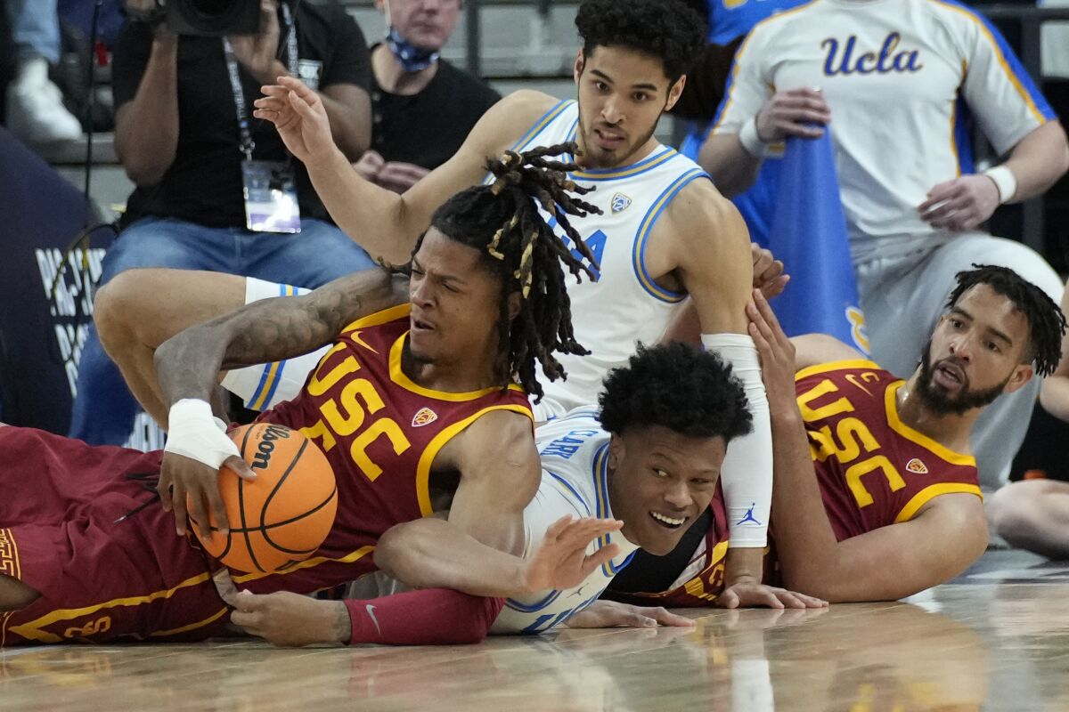 Southern California's Isaiah White, left, and UCLA's Jaylen Clark scramble for the ball during the first half of an NCAA college basketball game in the semifinal round of the Pac-12 tournament Friday, March 11, 2022, in Las Vegas. (AP Photo/John Locher)