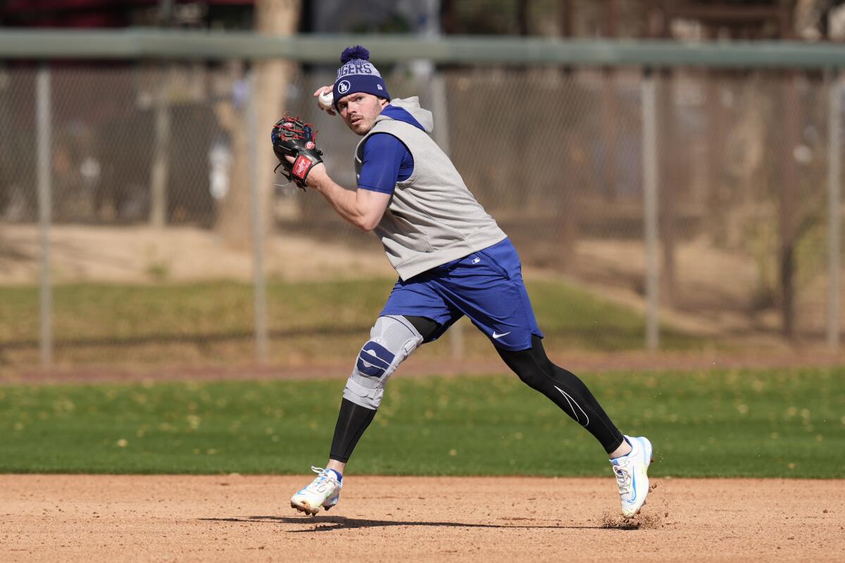 Dodgers shortstop Gavin Lux, wearing a knee brace, throws to first base at spring training on Friday.