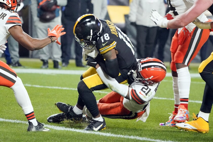 Pittsburgh Steelers wide receiver Diontae Johnson (18) scores a touchdown in front of Cleveland Browns cornerback Denzel Ward (21) after catching a pass in the first half of an NFL football game, Monday, Jan. 3, 2022, in Pittsburgh. (AP Photo/Gene J. Puskar)