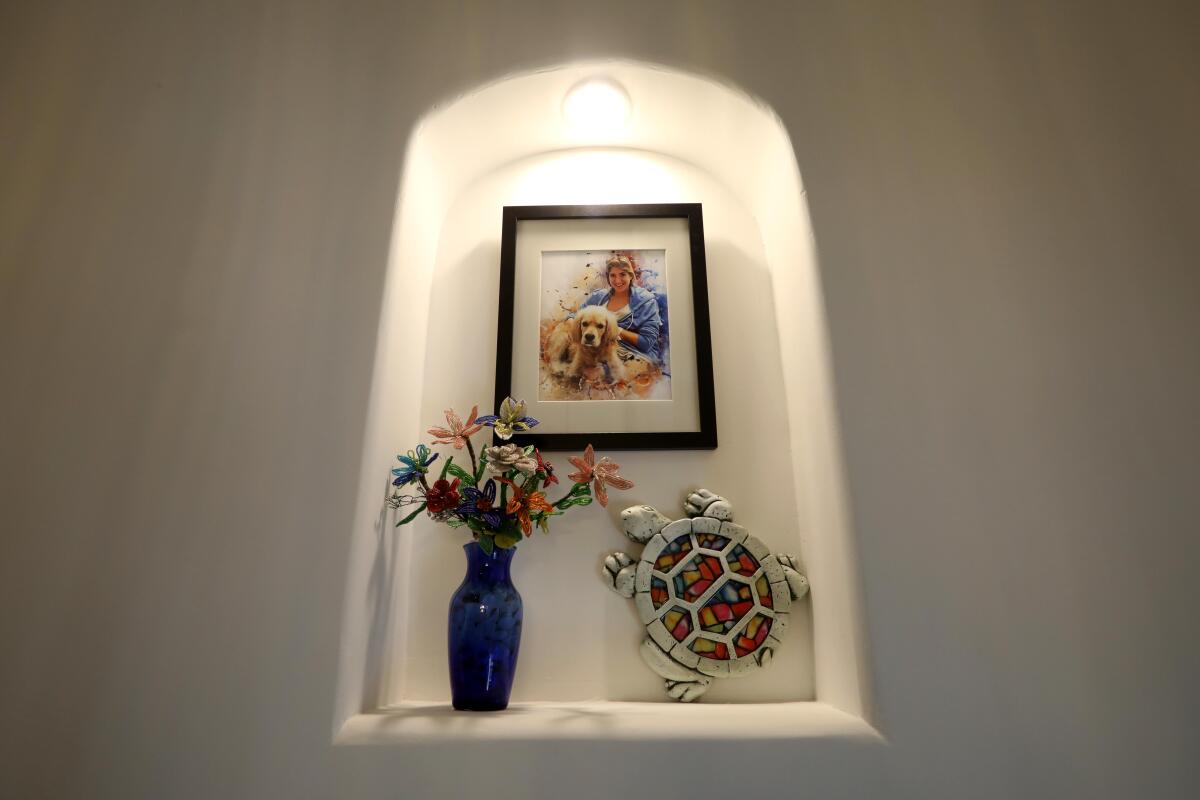 Flowers, a turtle sculpture and a picture of a woman are in a wall nook.