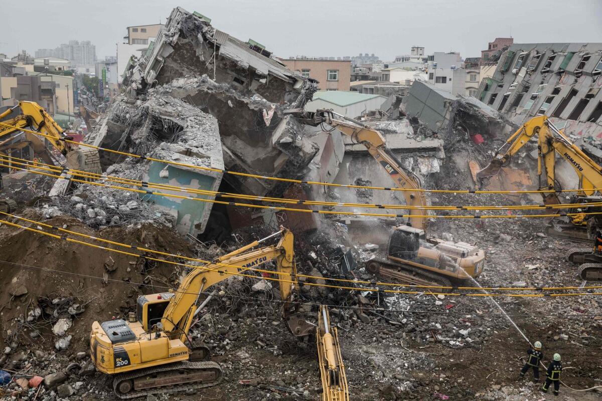 Firefighters hose down falling rubble on Feb. 10 to prevent dust from rising during the search and rescue operation at an apartment tower that collapsed in an earthquake four days earlier in the southern Taiwanese city of Tainan.