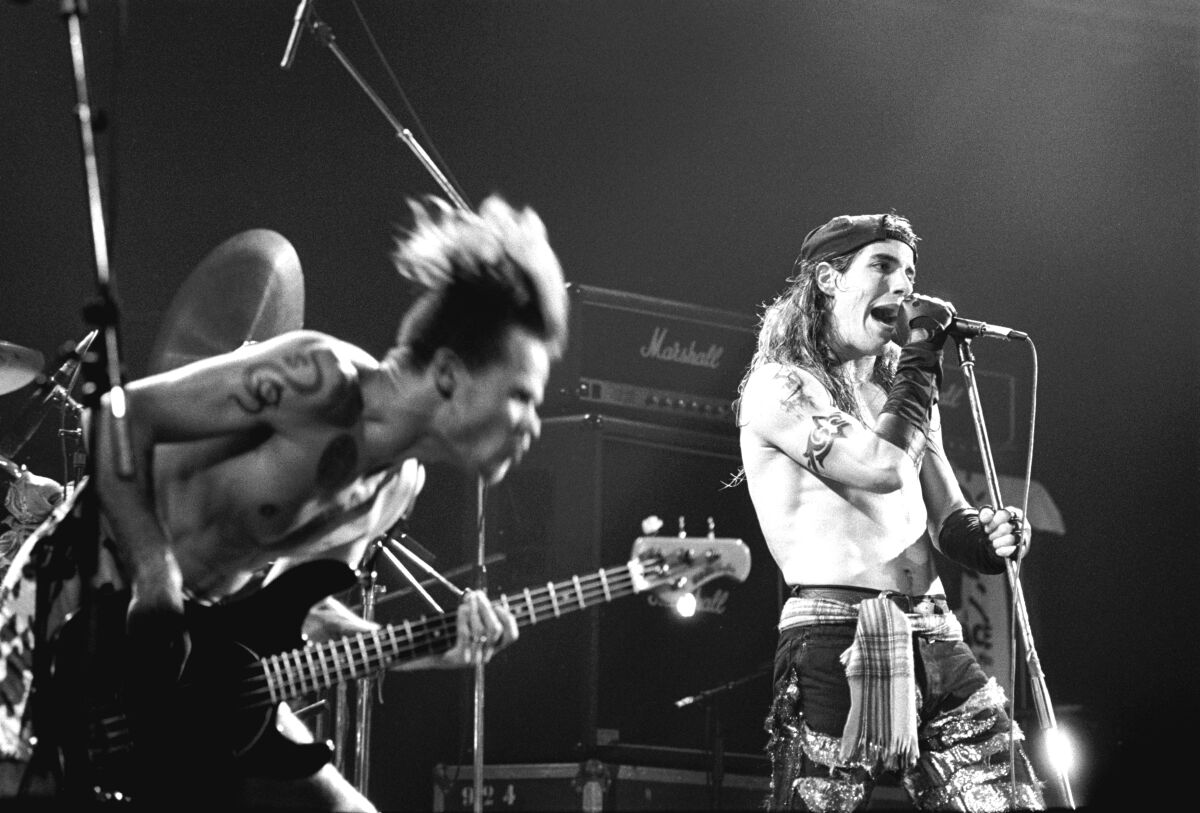 Two shirtless men in a rock band perform onstage