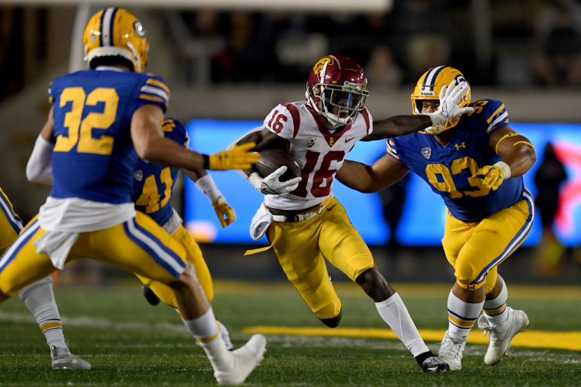 BERKELEY, CALIFORNIA - DECEMBER 04: Tahj Washington #16 of the USC Trojans stiff arms Luc Bequette.