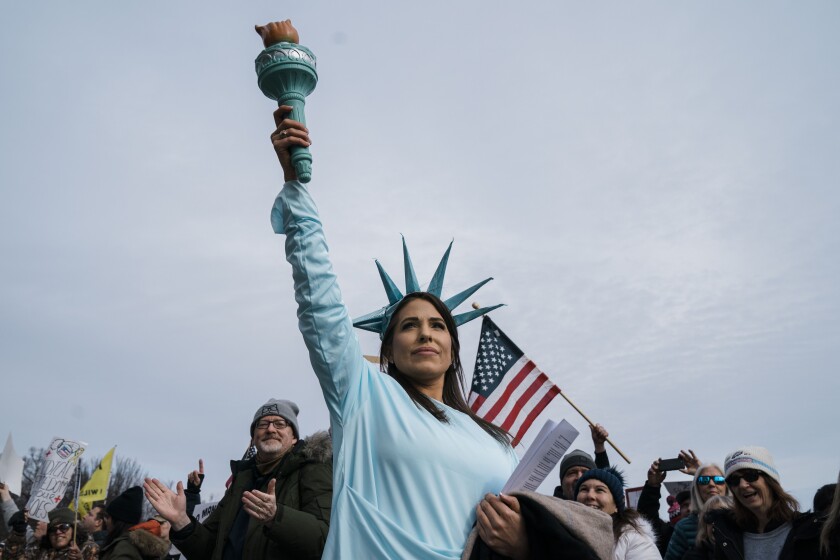 زنی که لباس مجسمه آزادی را در حین گردهمایی «شکست اختیارات» در مرکز خرید ملی ژست گرفته است.
